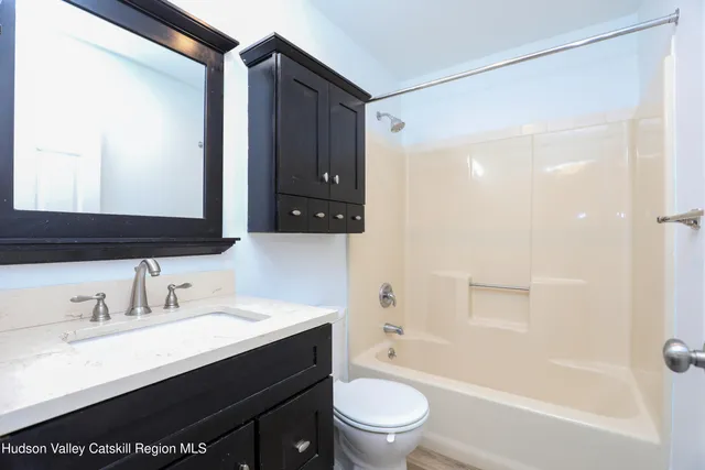 a bathroom with a bathtub shower sink vanity mirror and toilet
