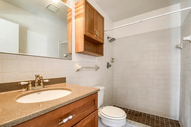 a bathroom with a granite countertop sink toilet a mirror and shower