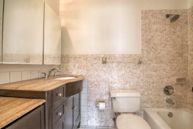 a bathroom with a granite countertop toilet a sink and a mirror