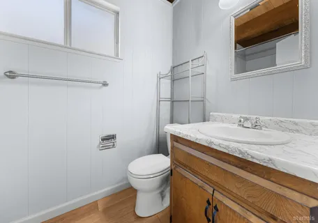 a bathroom with a granite countertop sink toilet and mirror