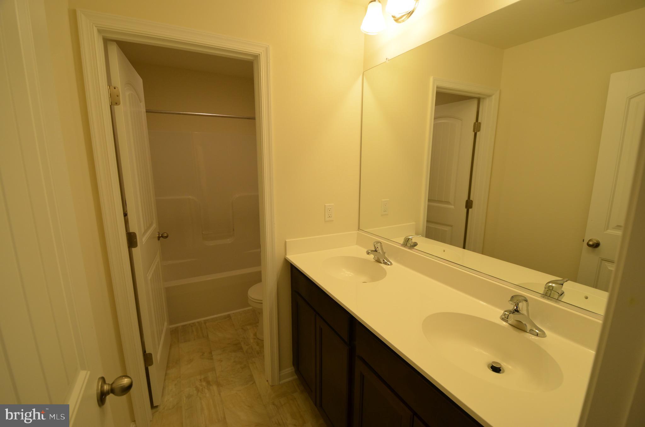 5917 Sneed Drive Deale, MD 20751 - Photo 14 of 26 a bathroom with a double vanity sink mirror and shower