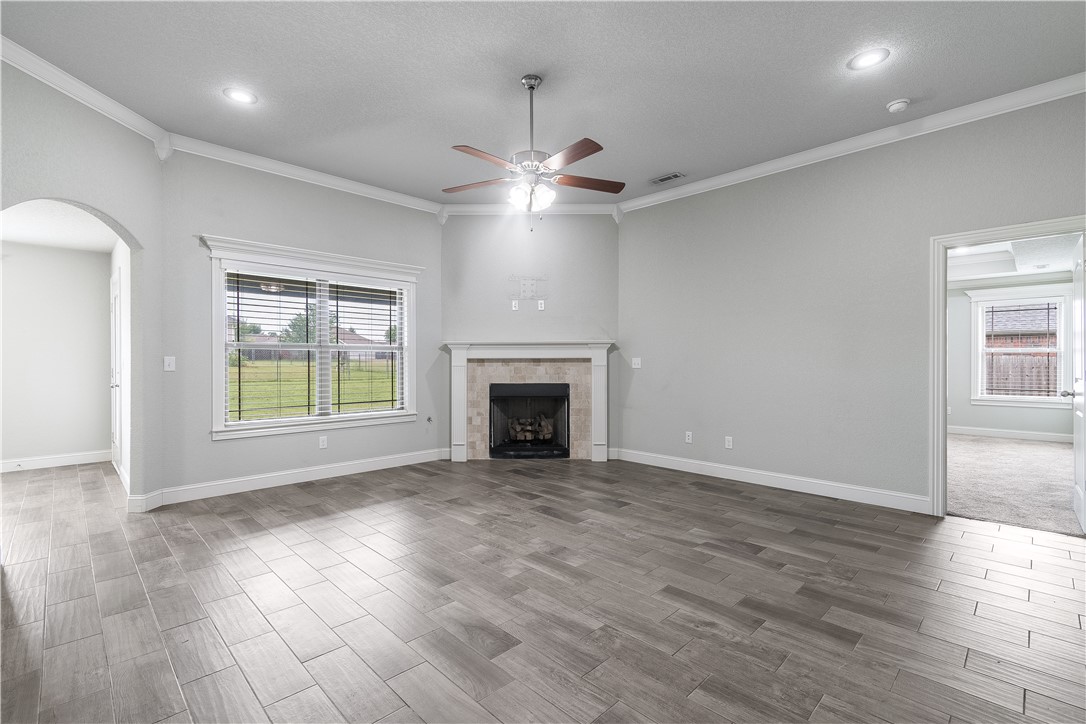 457 Harper Drive Pea Ridge, AR 72751 - Photo 13 of 22 Spacious living area featuring wood-finish flooring, a recessed fireplace with a stone surround and white mantel, and a multi-speed ceiling fan