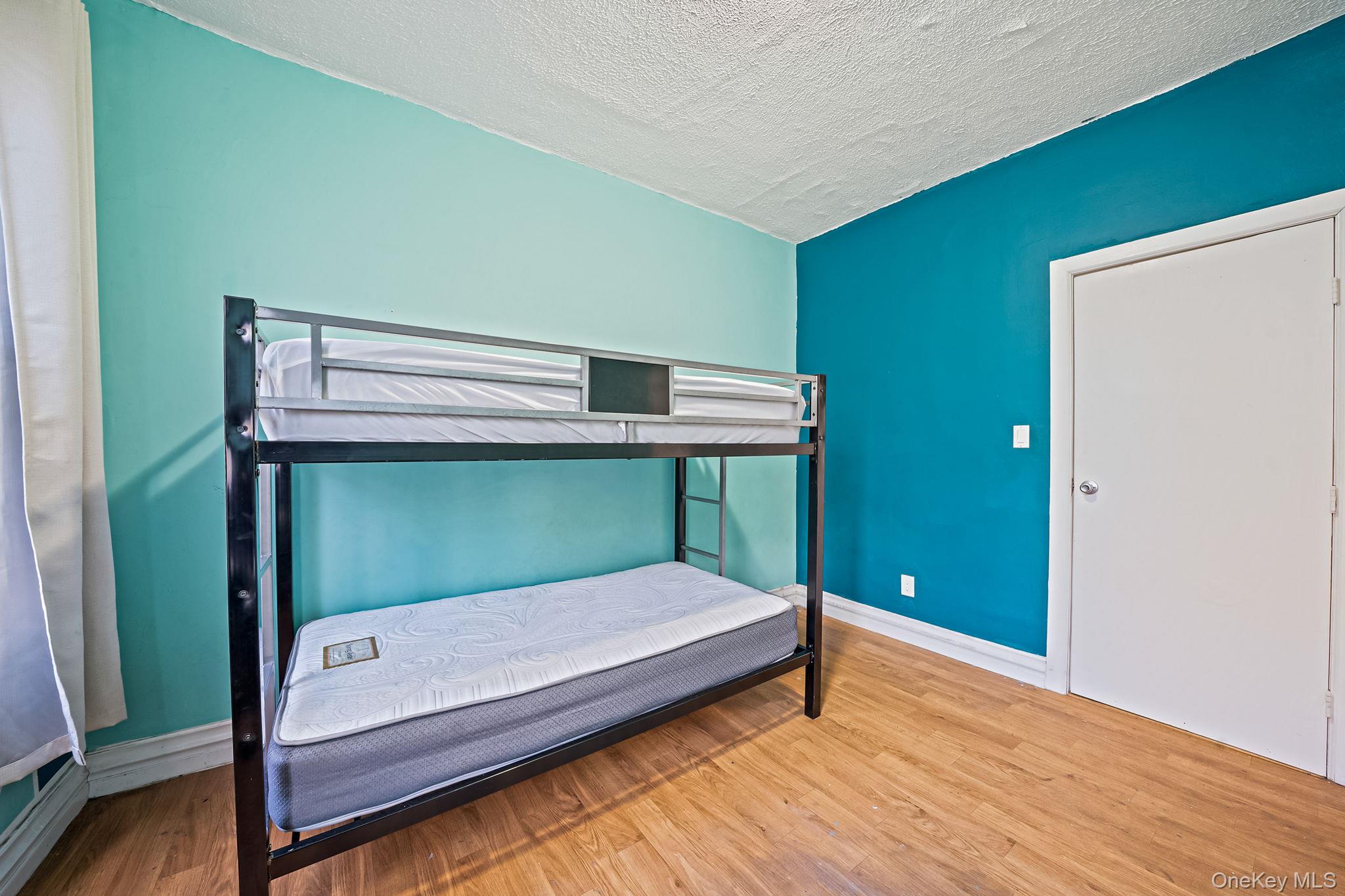 108-76 38th Avenue Queens, NY 11368 - Photo 11 of 38 a bedroom with a bed and wooden floor