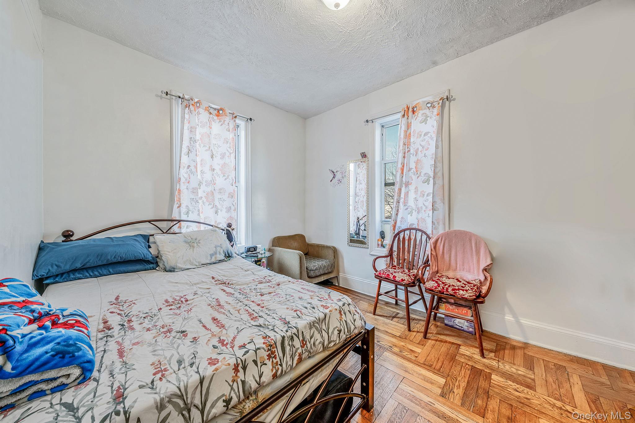 108-76 38th Avenue Queens, NY 11368 - Photo 19 of 38 a bedroom with two beds and a chair