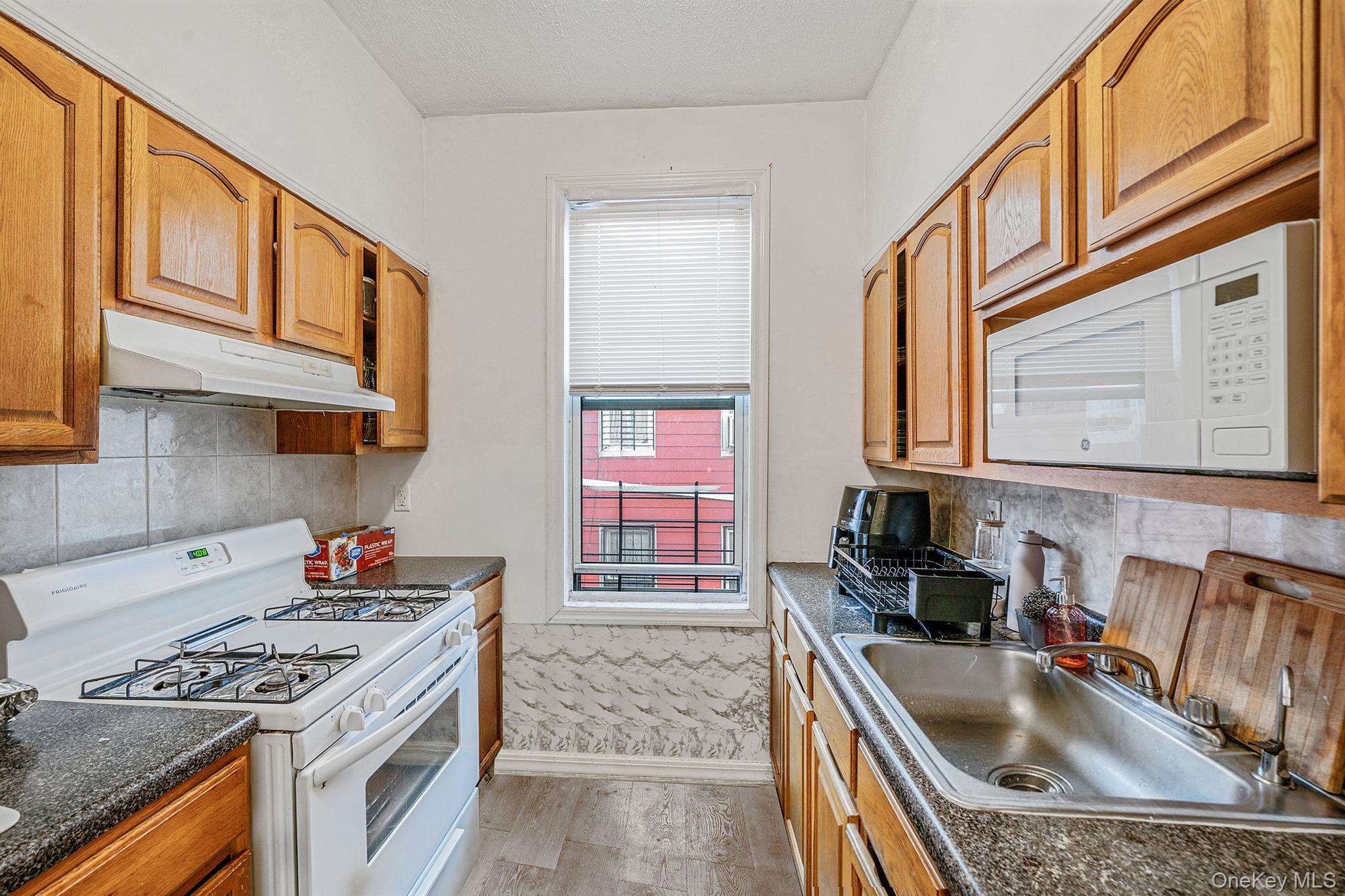 108-76 38th Avenue Queens, NY 11368 - Photo 20 of 38 a kitchen that has a sink a stove and wooden cabinets