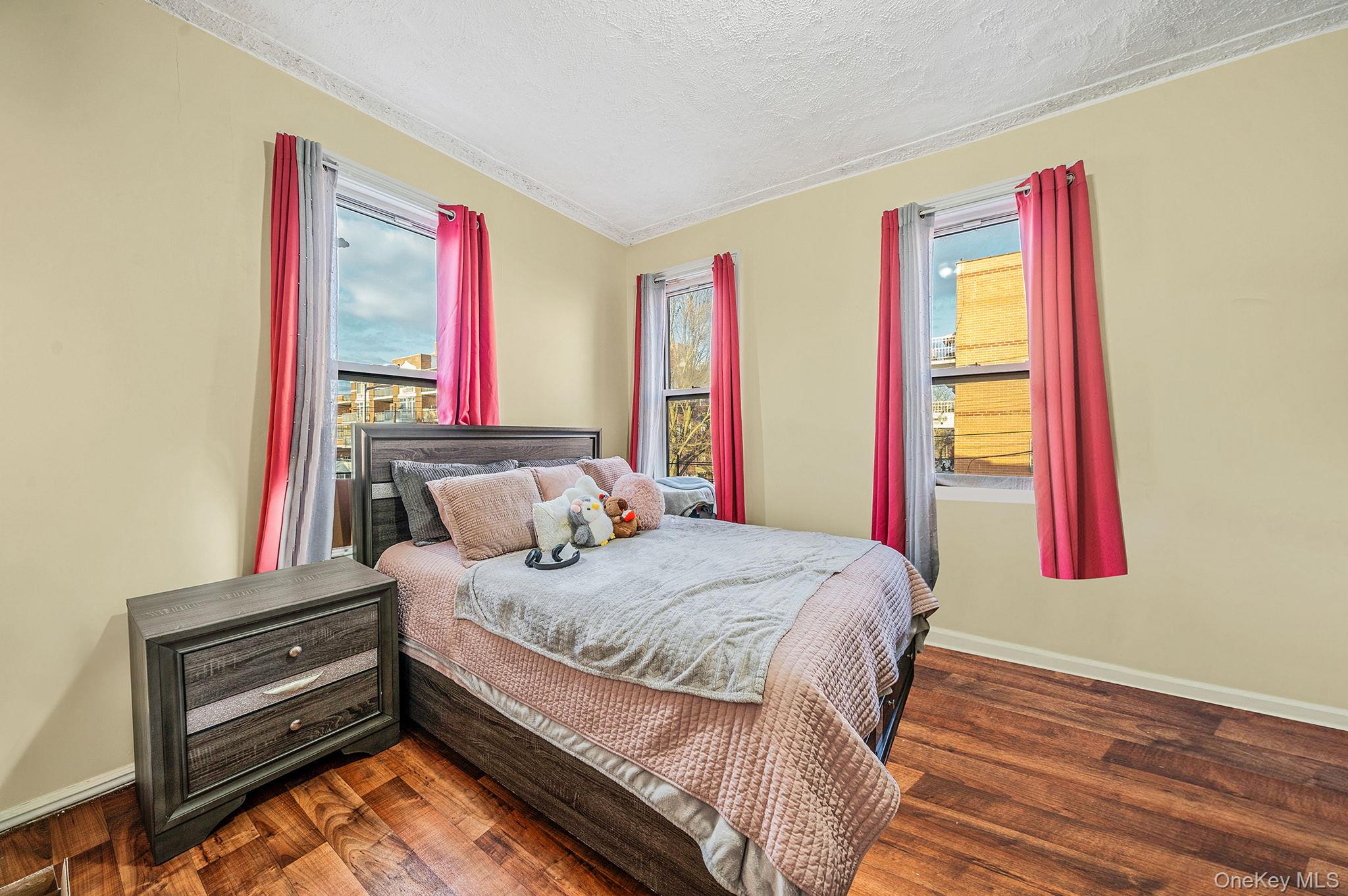 108-76 38th Avenue Queens, NY 11368 - Photo 28 of 38 a bedroom with a bed and a dresser next to a window