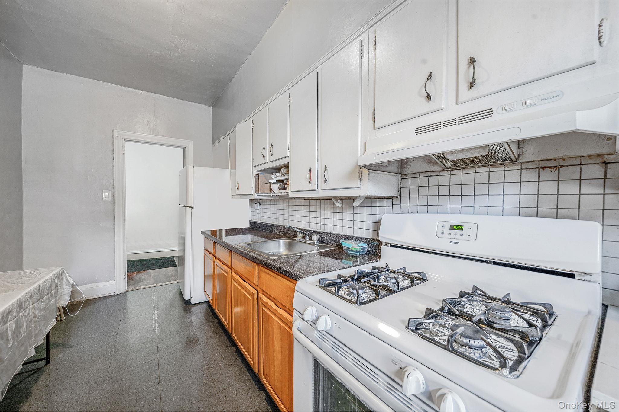 108-76 38th Avenue Queens, NY 11368 - Photo 31 of 38 a kitchen with a stove and white cabinets