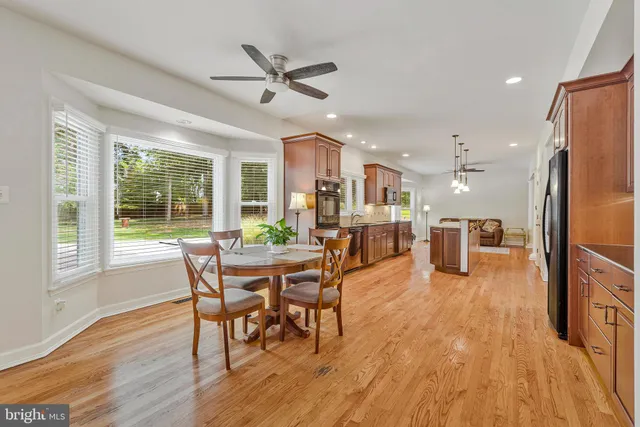 a kitchen with stainless steel appliances granite countertop a refrigerator a stove top oven a sink dishwasher and white cabinets with wooden floor