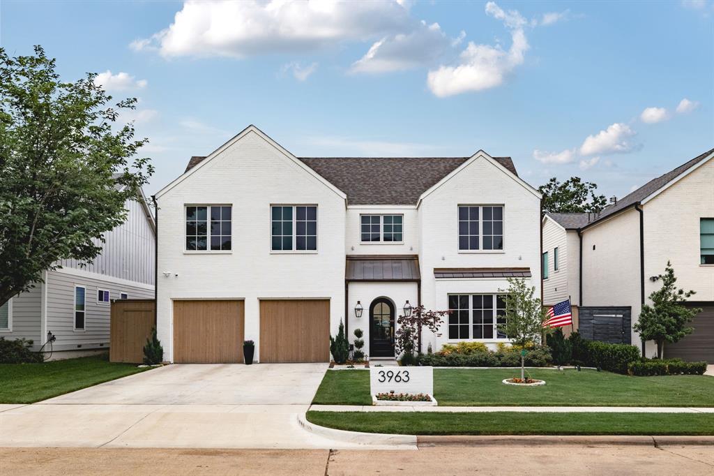 White brick exterior with a dark shingle roof, two wood-finish garage doors, and a concrete driveway