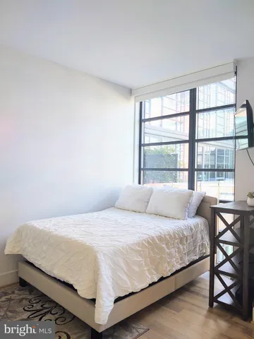 a bedroom with a bed a table and a large window