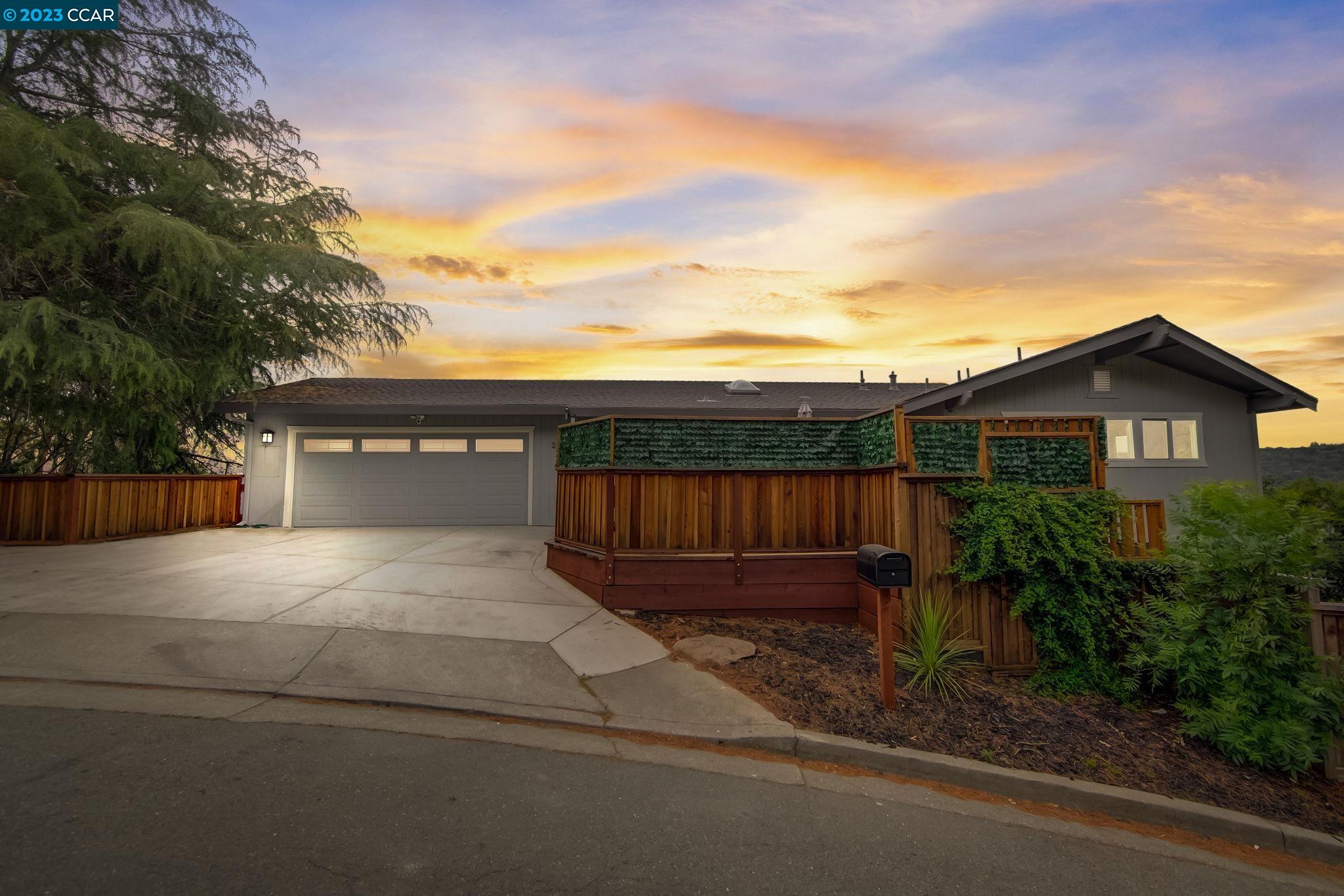 a view of a house with a yard plants and large tree