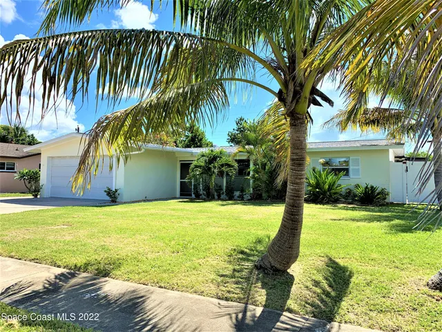 a view of a house with a yard and palm trees
