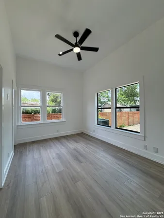 a view of empty room with wooden floor and fan