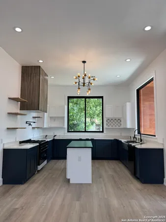 a kitchen with kitchen island granite countertop a sink window and cabinets