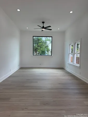 an empty room with wooden floor chandelier and windows