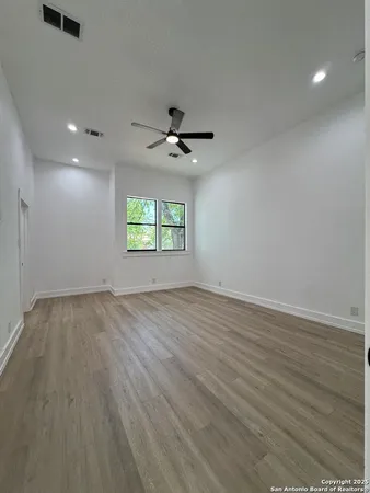 an empty room with wooden floor and windows