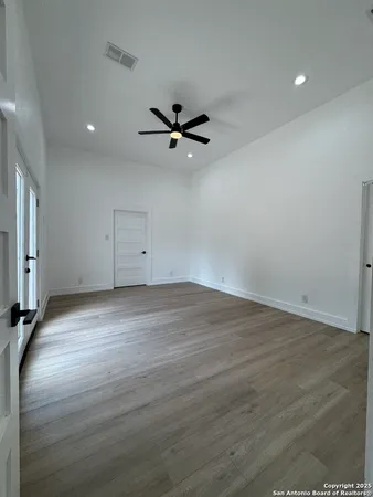 an empty room with wooden floor ceiling fan and window