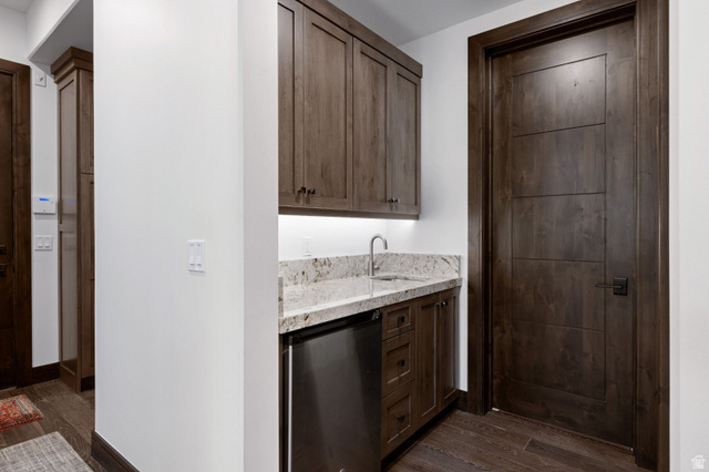 11547 Soaring Hawk Lane Hideout, UT 84036 - Photo 33 of 43 Wet bar featuring dark wood cabinetry, a light-toned granite countertop, and a stainless steel sink with a gooseneck faucet