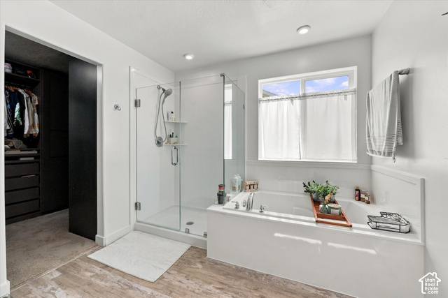 7939 Seattle Slew Road Eagle Mountain, UT 84005 - Photo 20 of 52 Built-in soaking tub, glass-enclosed shower, wood-finish flooring, recessed lighting, and built-in closet storage