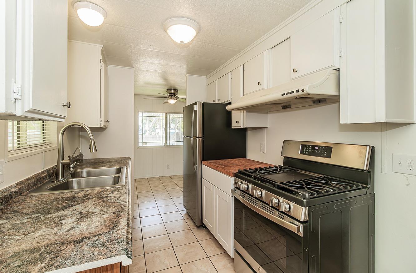 a kitchen with granite countertop a stove a sink dishwasher and a refrigerator