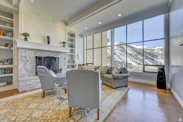 9699 Bypass Road, Unit 5 Alta, UT 84092 - Photo 14 of 54 Living area featuring expansive floor-to-ceiling windows, a stone-clad fireplace, integrated built-in shelving, recessed lighting, and wood-finish flooring