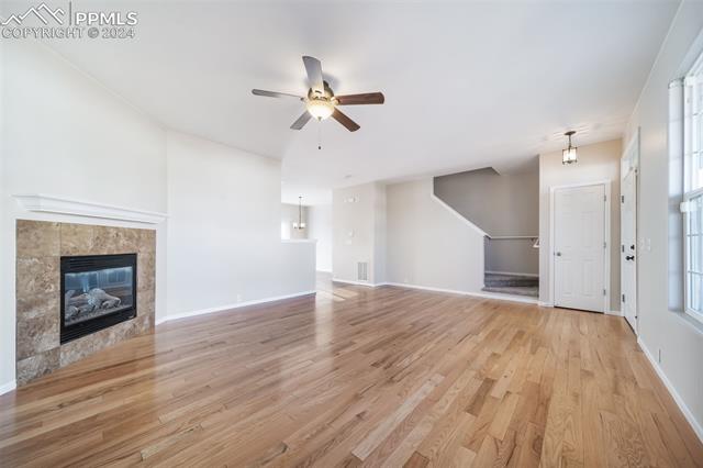 9356 Bethpage Road Peyton, CO 80831 - Photo 9 of 40 Unfurnished living room featuring ceiling fan, light wood-type flooring, and a tiled fireplace