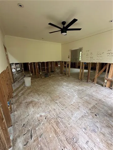 an empty room with wooden floor and a ceiling fan