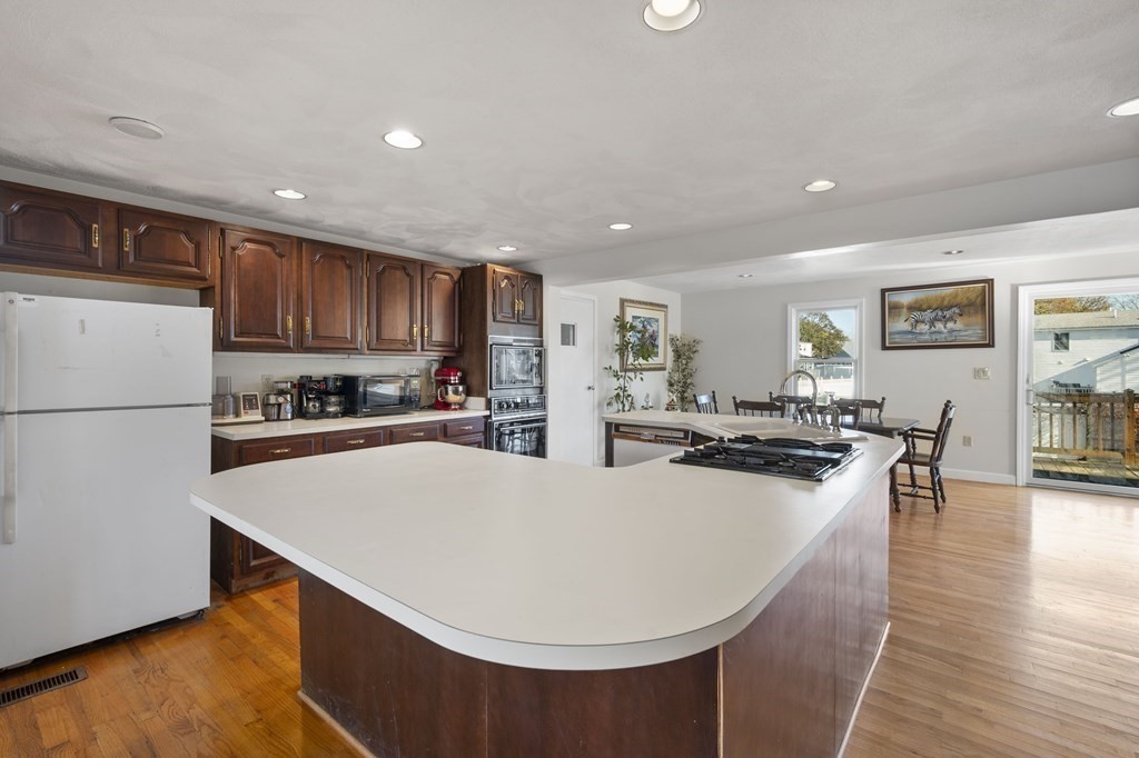 59 Proctor Circle Peabody, MA 01960 - Photo 6 of 32 a kitchen with stainless steel appliances a stove a refrigerator a stove a sink a dining table and chairs with wooden floor