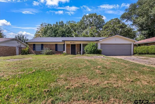 a view of a house with a yard and large trees