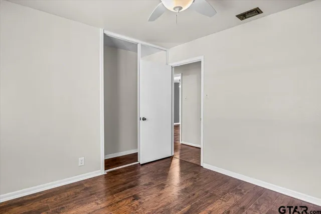 an empty room with wooden floor and a ceiling fan