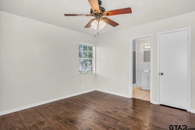an empty room with wooden floor ceiling fan and window