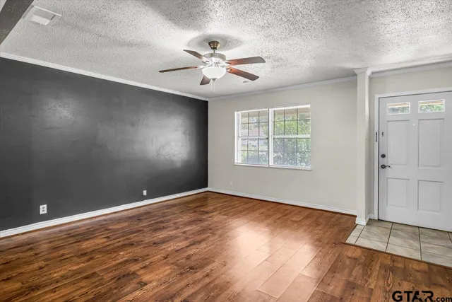 an empty room with wooden floor chandelier fan and windows