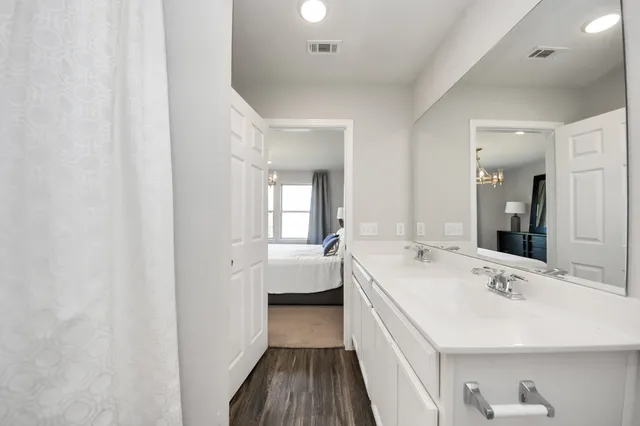 a large white room with a double vanity sink and mirror