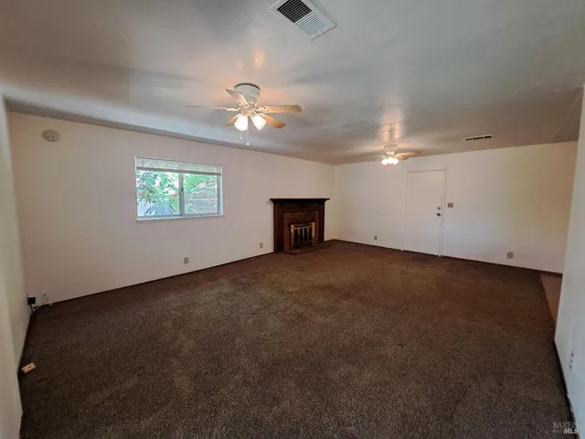 a view of a livingroom with a fireplace a ceiling fan and wooden floor