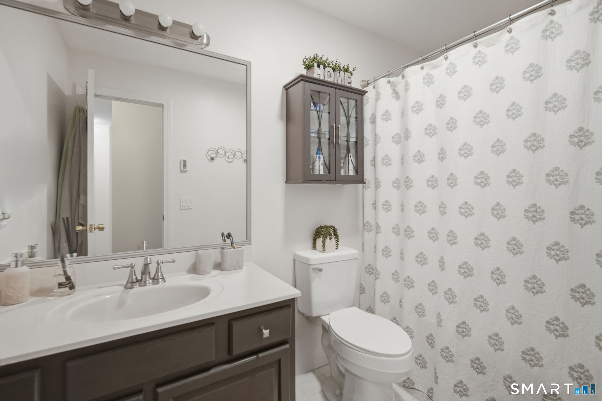 350 Bristol Street, Unit C12 Waterbury, CT 06708 - Photo 20 of 40 a bathroom with a granite countertop toilet a sink a mirror and a shower curtain