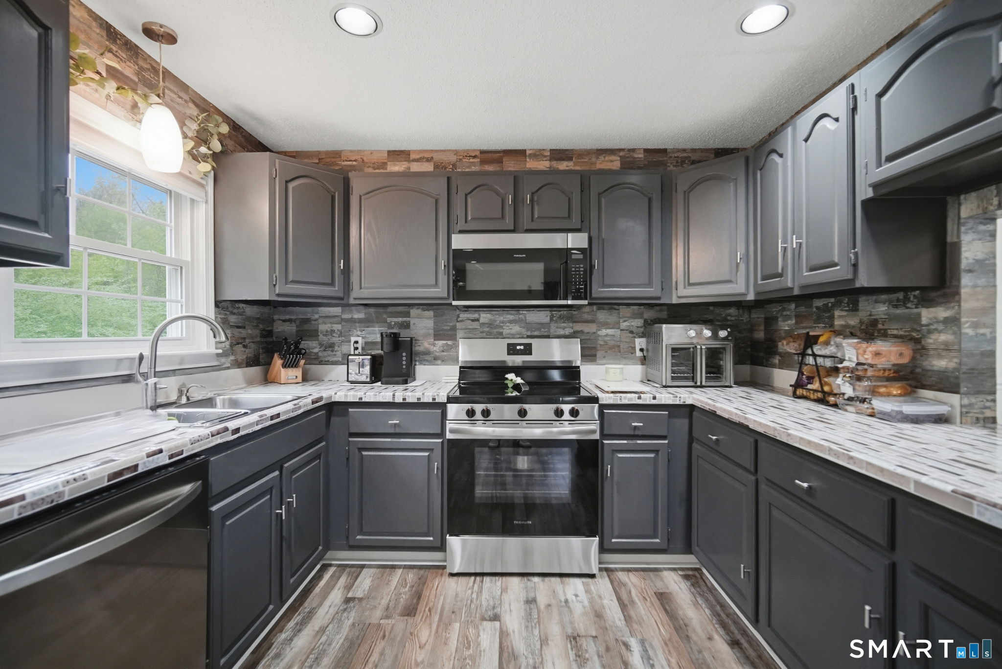 350 Bristol Street, Unit C12 Waterbury, CT 06708 - Photo 10 of 40 a kitchen with stainless steel appliances granite countertop a sink a stove top oven a refrigerator cabinets and a window