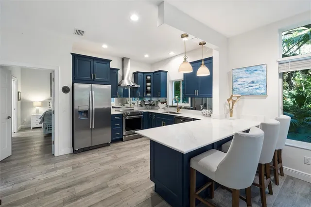 a kitchen with stainless steel appliances a dining table chairs and wooden floor