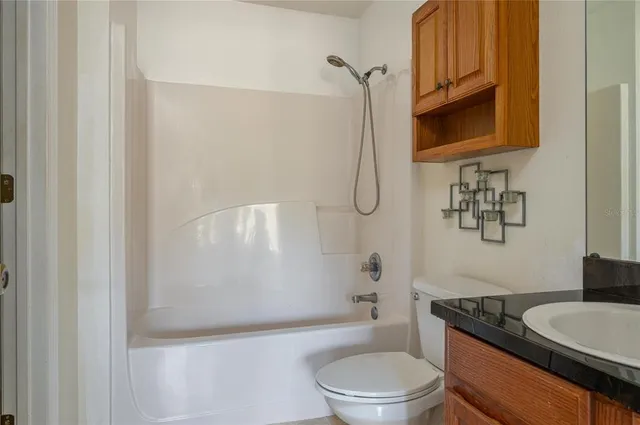 a bathroom with a granite countertop bathtub shower sink mirror vanity and toilet