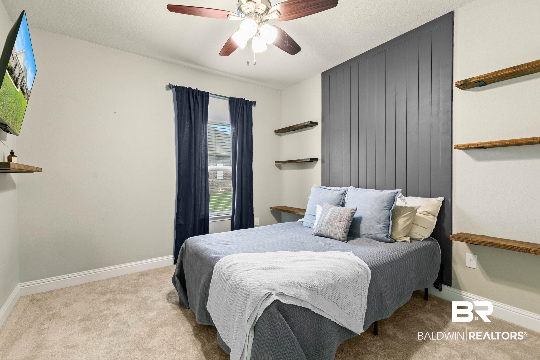 31187 Spoonbill Road Daphne, AL 36527 - Photo 40 of 85 Bedroom featuring a dark gray vertical panel accent wall, recessed window with dark drapery, and a ceiling fan with light fixture