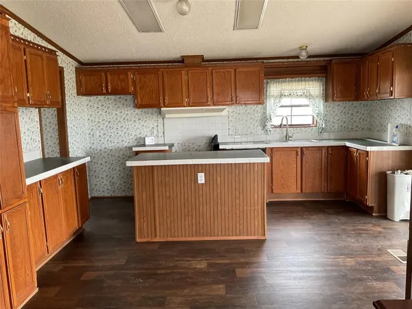 a kitchen with stainless steel appliances granite countertop wooden cabinets a stove a sink and dishwasher with wooden floor