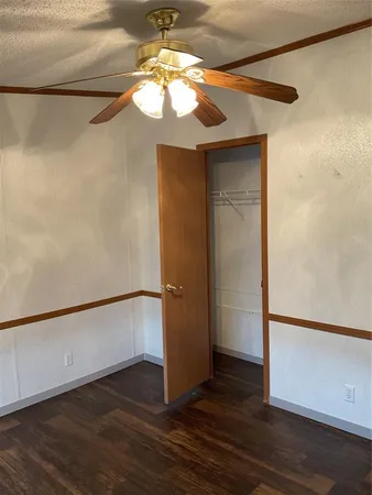 an empty room with wooden floor chandelier and windows