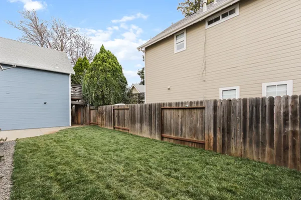 a brick house with a small yard and wooden fence