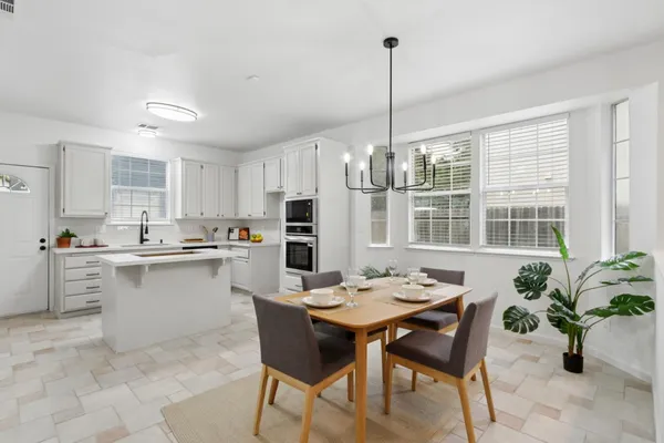 a open dining room with stainless steel appliances kitchen island granite countertop a table chairs and a view of living room