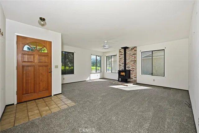 a view of an empty room with staircase and kitchen view