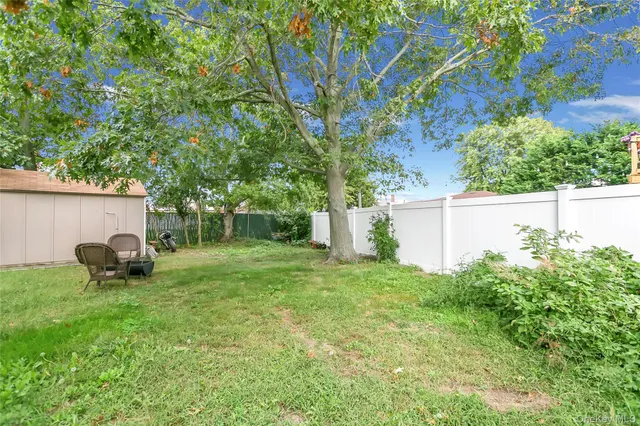 a backyard of a house with lawn chairs and a large tree