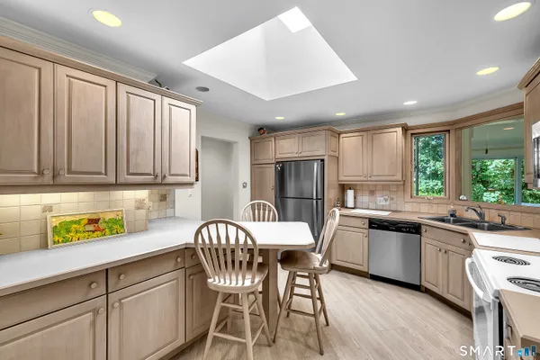 a kitchen with stainless steel appliances granite countertop a dining table chairs refrigerator and sink