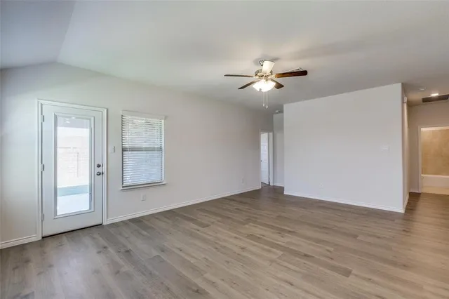 a view of empty room with wooden floor and fan