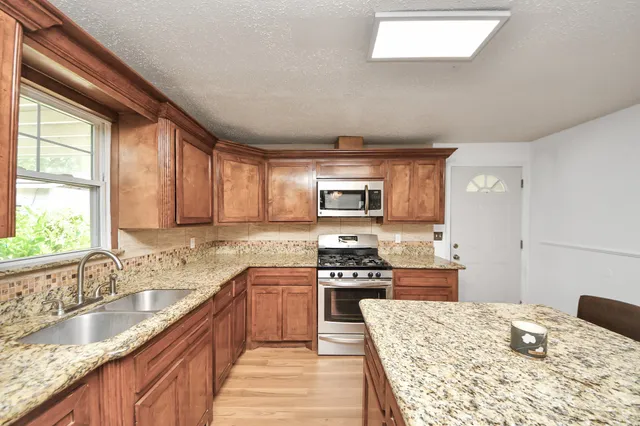 a kitchen with granite countertop a sink stove and refrigerator
