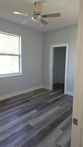 an empty room with wooden floor cabinet and windows
