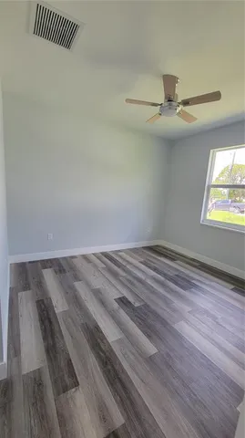 en empty room with wooden floor fan and windows
